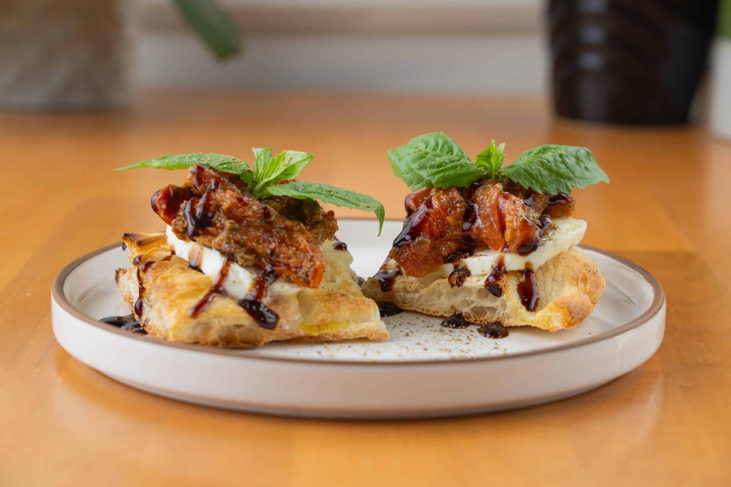 Delicious vegan pizza slices topped with fresh basil and balsamic glaze, served in a charming Italian cafe.