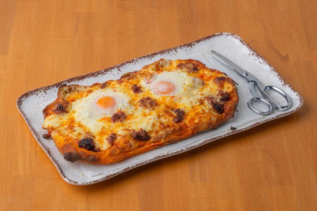 Delicious eggs Benedict-inspired pizza with crispy edges, melted cheese, and perfectly cooked eggs.